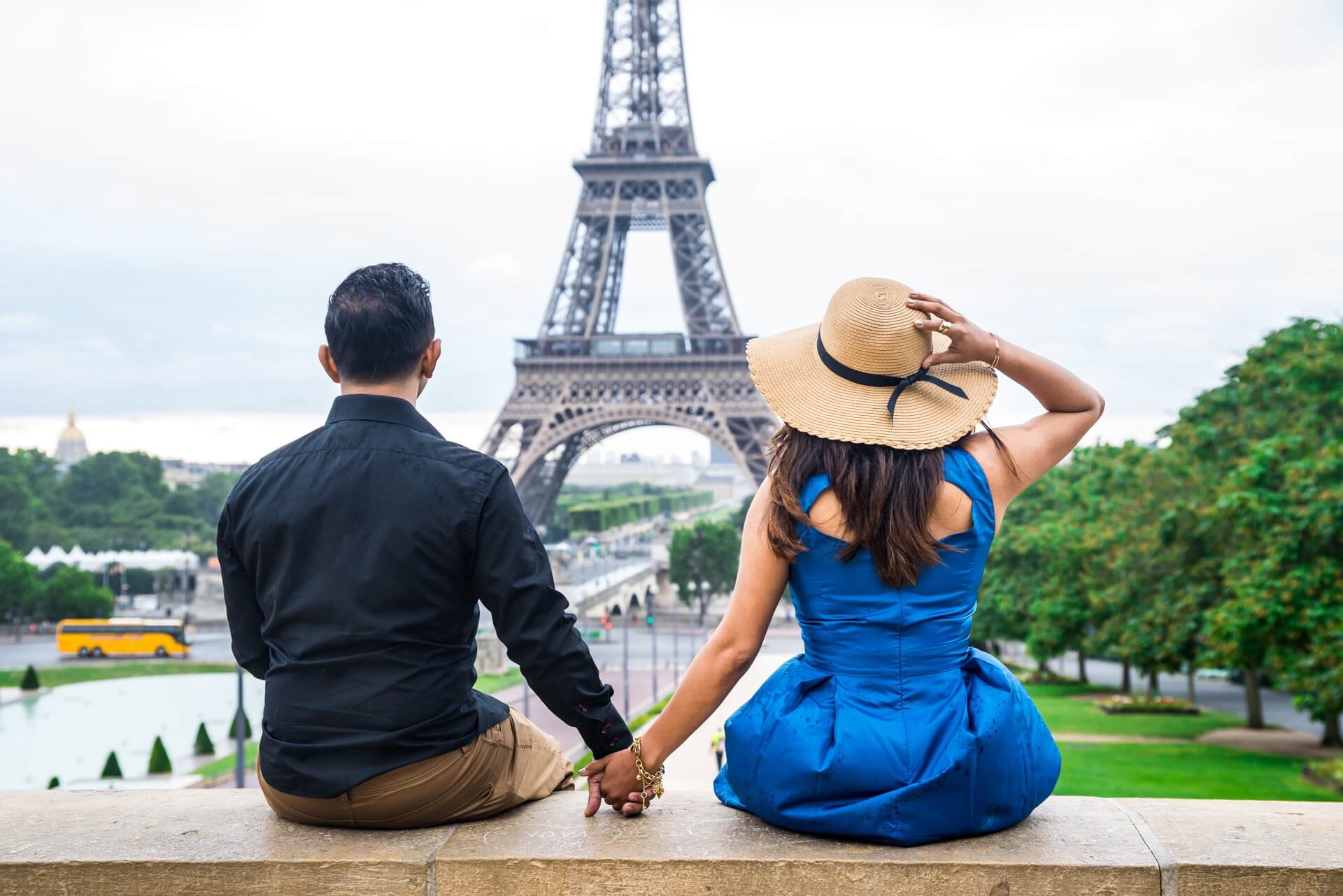 Photo with one guy and one girl holding their hands in front of Eiffel Tower